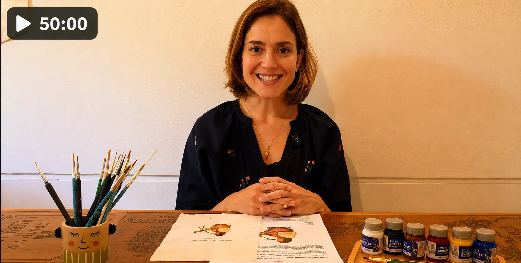 Maria Paixão sorrindo em sua mesa de trabalho